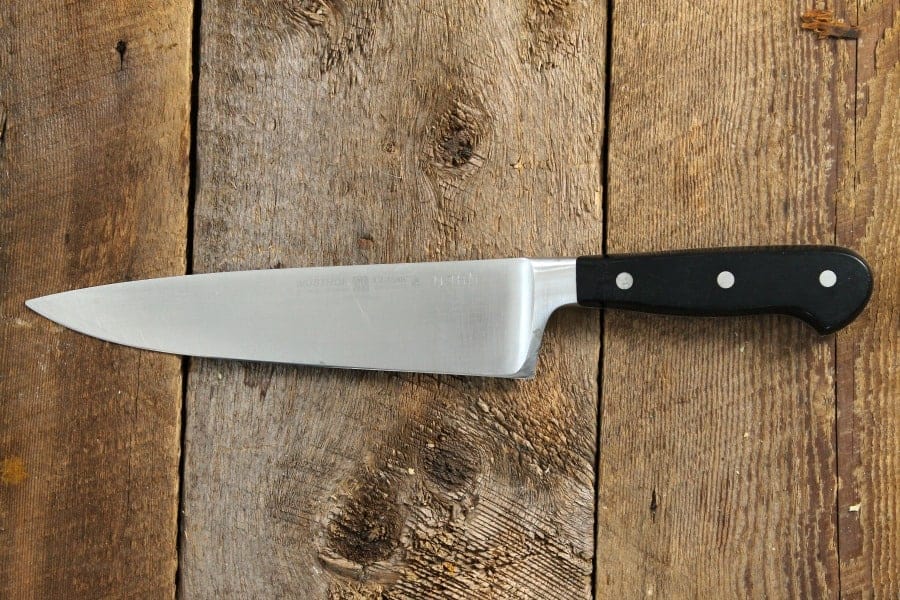 A wusthof chefs knife on a wood board tabletop