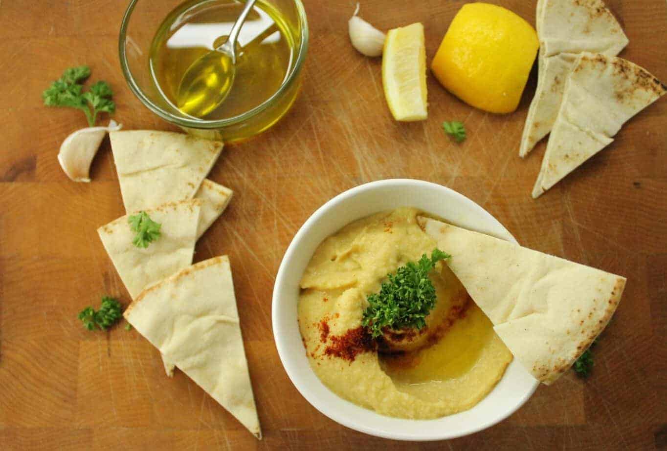 Hummus Without Tahini Dip on a cutting board with pita garlic and lemon