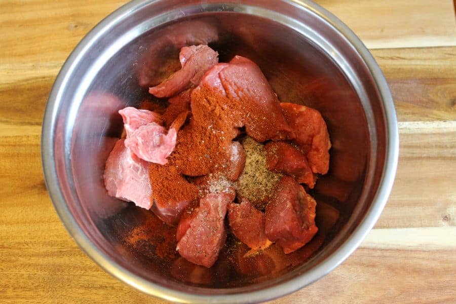 Diced Beef chuck marinating in a bowl with various spices.