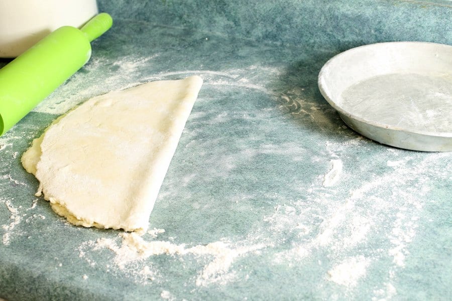 raw pie dough folded in half in preparation of moving it to a pie pan