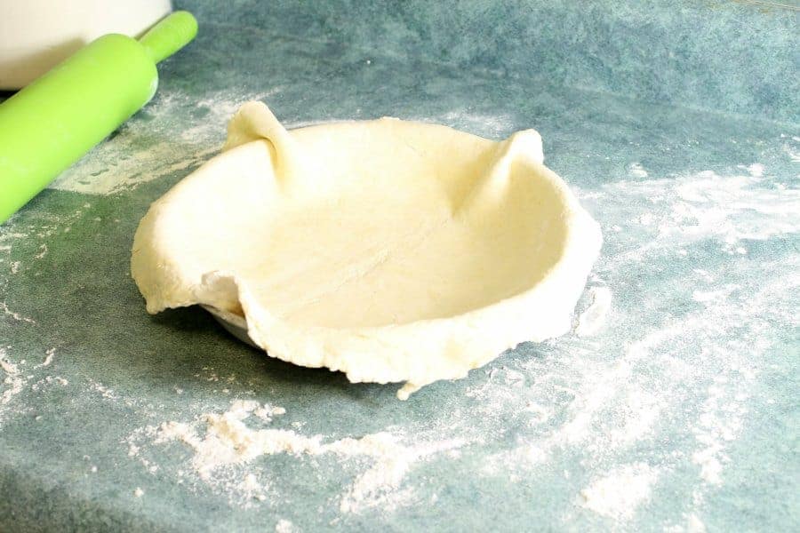 a raw pie crust fully transferred to a pie pan, with the edges not yet crimped