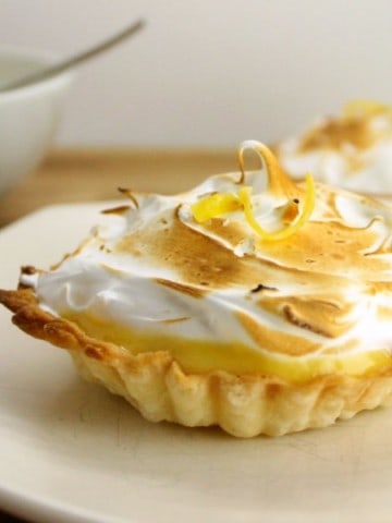 2 lemon meringue tarts on plates