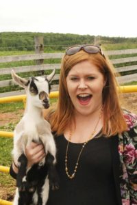 Stephanie holding a baby goat at Island Hill Farm in PEI.