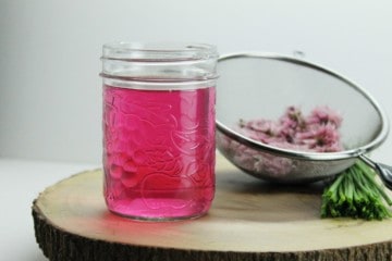 Home made chive blossom vinegar is a great way to us up excess chive flowers from your garden. Simple to make this homemade condiment, produces a stunning color! Great for use in marinades, dressings, and sauces!