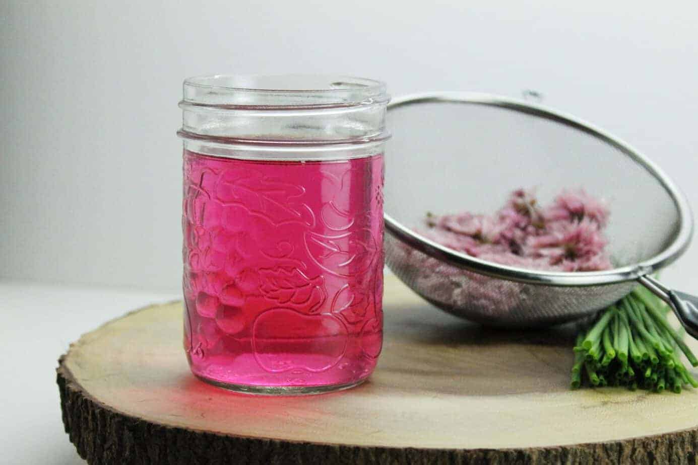 Home made chive blossom vinegar is a great way to us up excess chive flowers from your garden. Simple to make this homemade condiment, produces a stunning color! Great for use in marinades, dressings, and sauces!