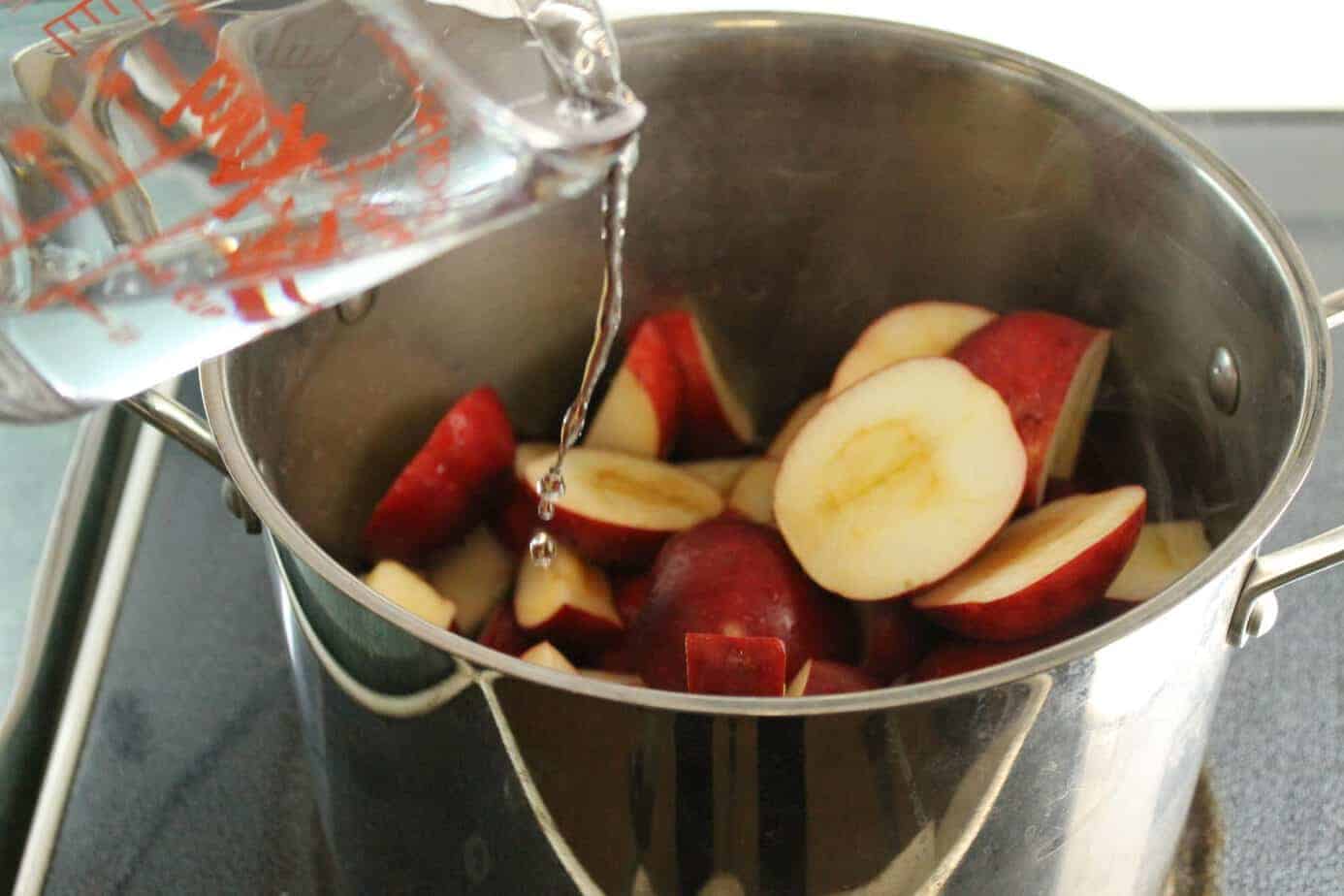 chopped apples going mixed in a deep pot with water to be turned into apple butter