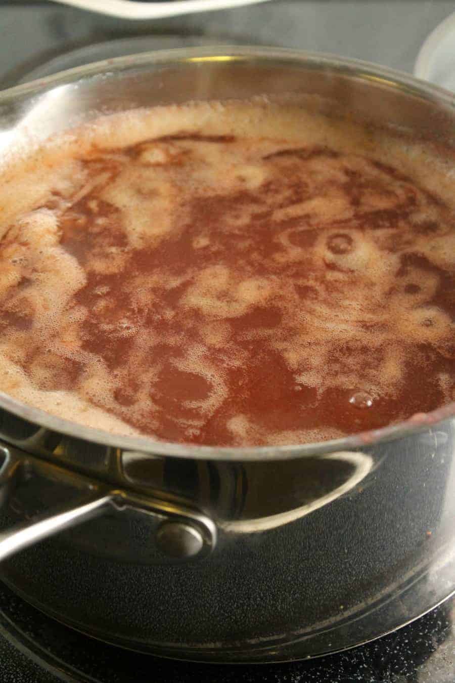 a pot of apple butter bubbling away on the stove as it cooks over very low heat.