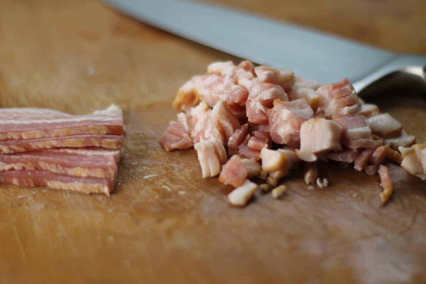 Diced raw bacon on a wooden cutting board