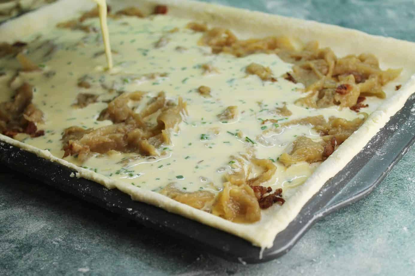 Pouring the filling onto these german caramelized onion tarts is the last step before baking at 325F for 1 hour.