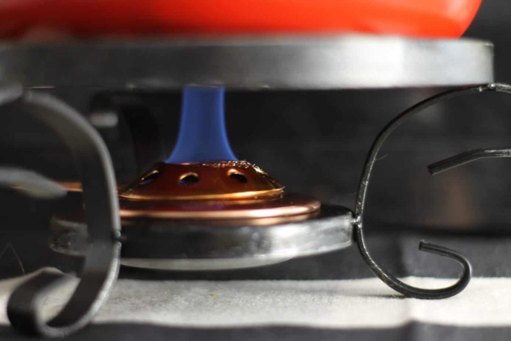 A blue flame burning underneath of a fondue pot