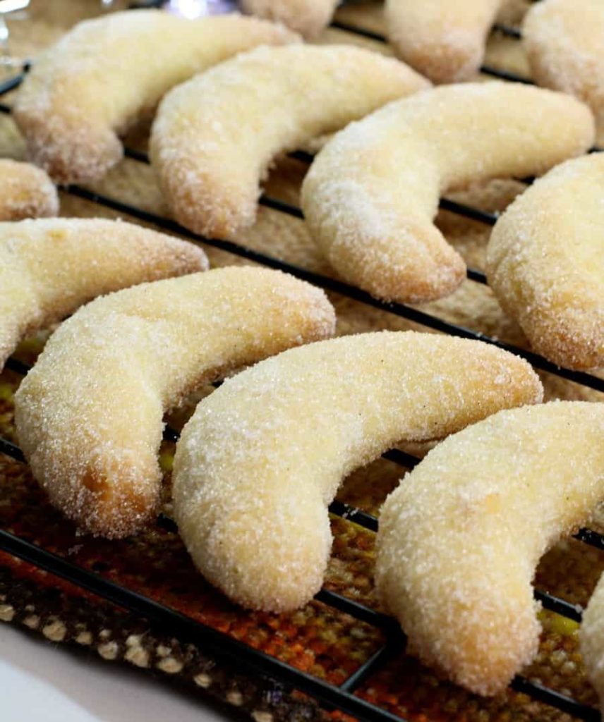 a close up shot of german vanillekipferl cookies on a black wire rack
