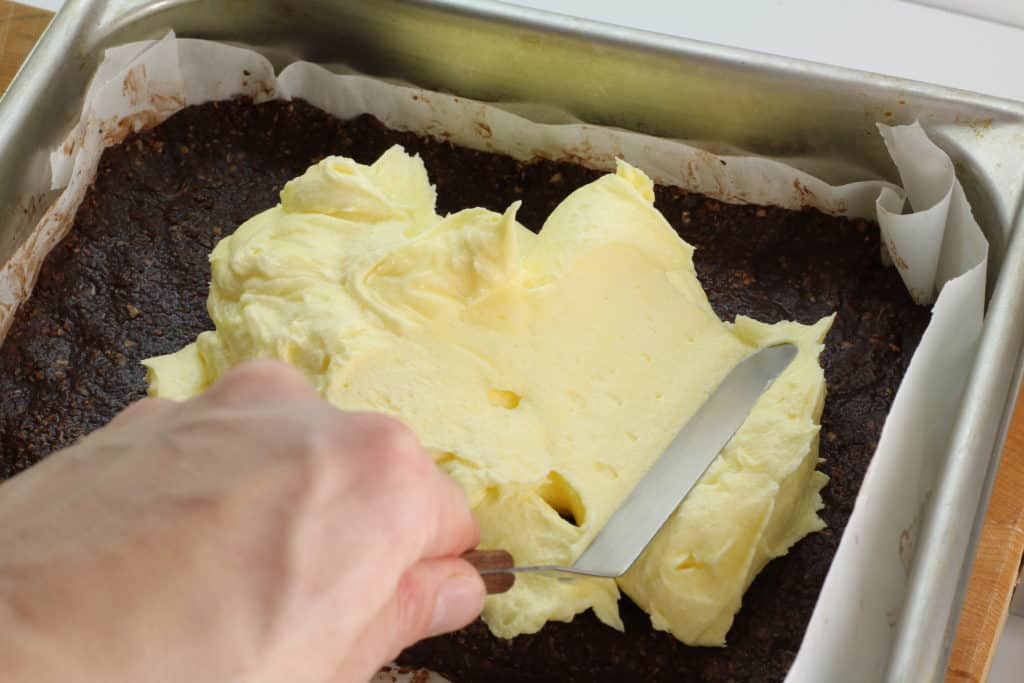 spreading the butetrcream icing on the homemade nanaimo bars