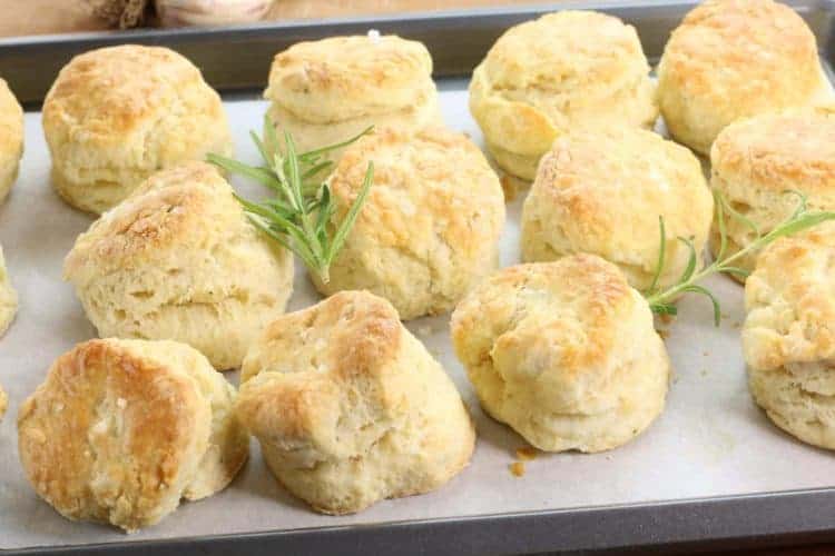 Homemade Rosemary & Garlic biscuits on a parchment lined sheet tray.