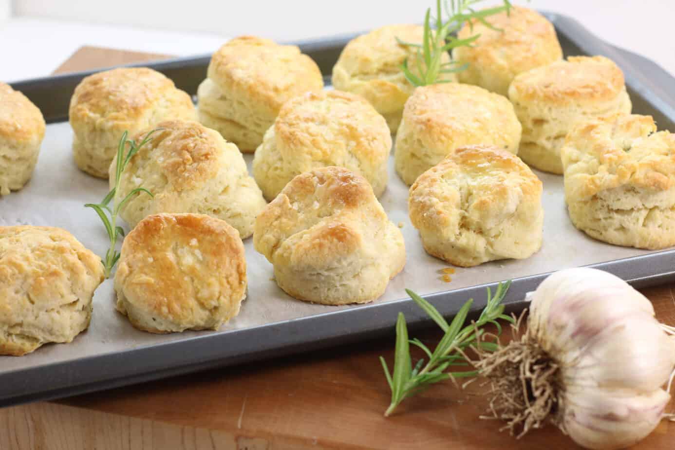 Freshly baked rosemary and garlic biscuits on a sheet tray.