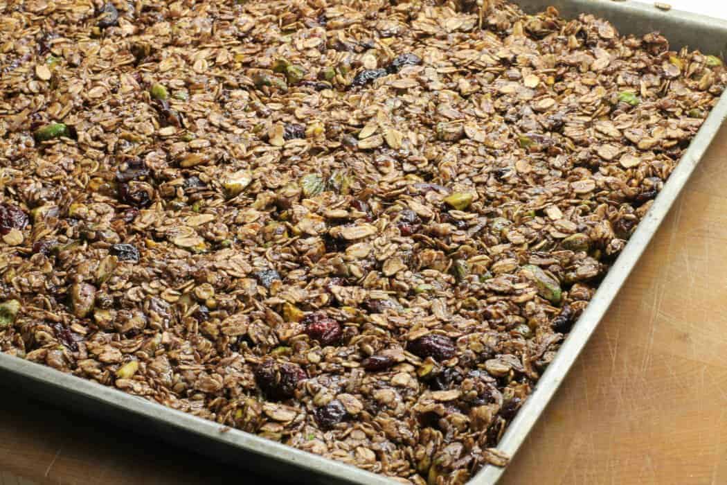 Homemade granola bar mixture spread on a sheet pan before baking at 300F for 30 minutes.