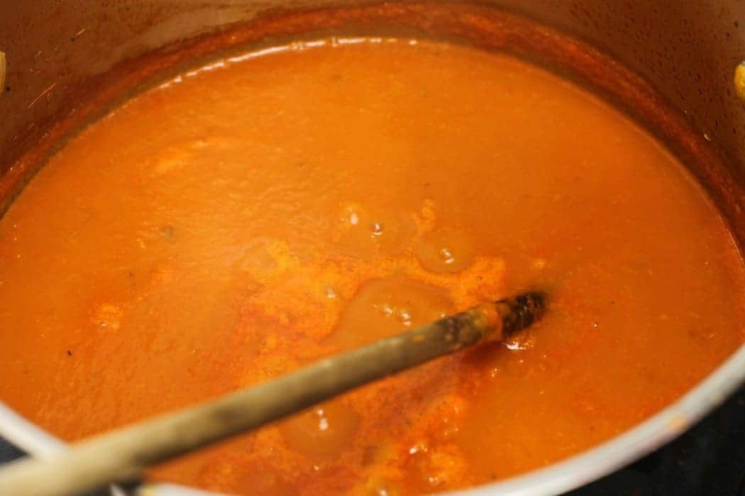 Pureed tomato sauce bubbling in a pot as it simmers on low