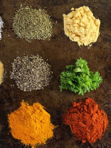 various essential spices in little piles on a dark background