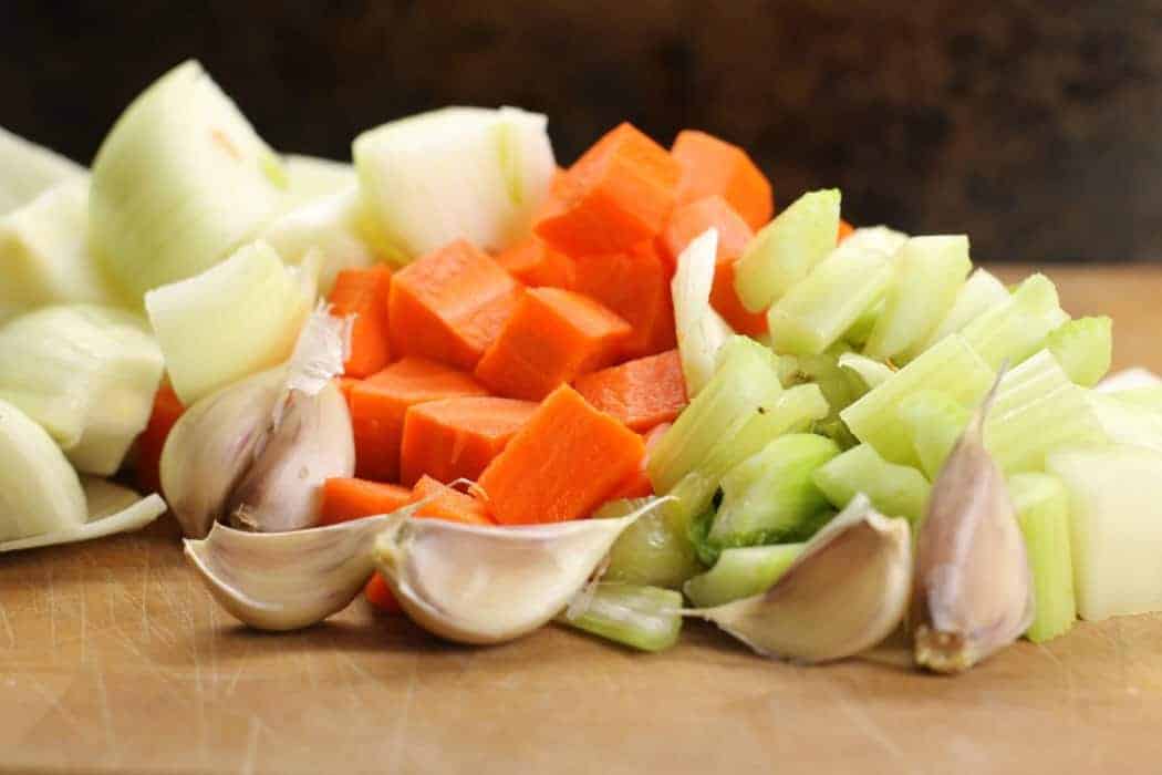 a Mirepoix mix on a wooden cutting board, a simple vegetable mix used in making stocks and broths