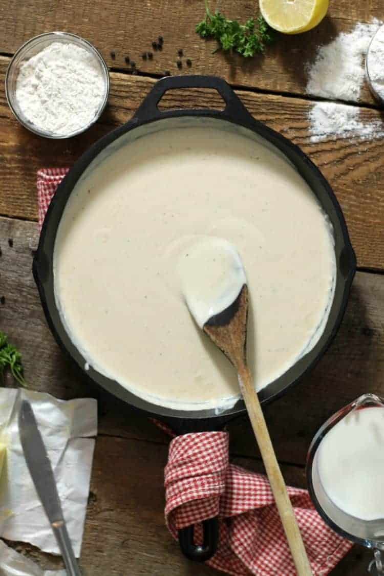 vertical image of bechamel sauce in a cast iron pan