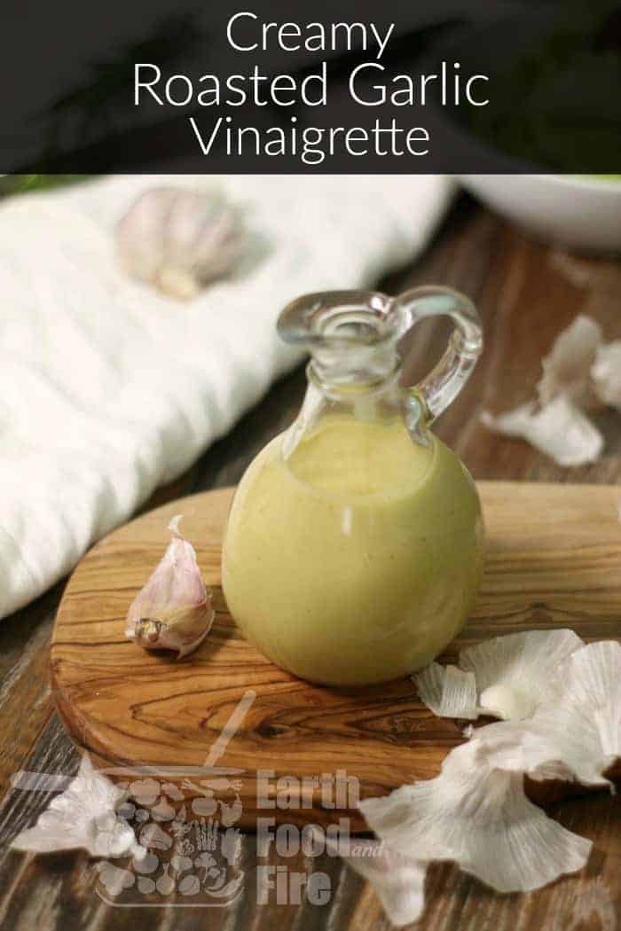 A bottle of homemade roasted garlic vinaigrette on a wooden serving board