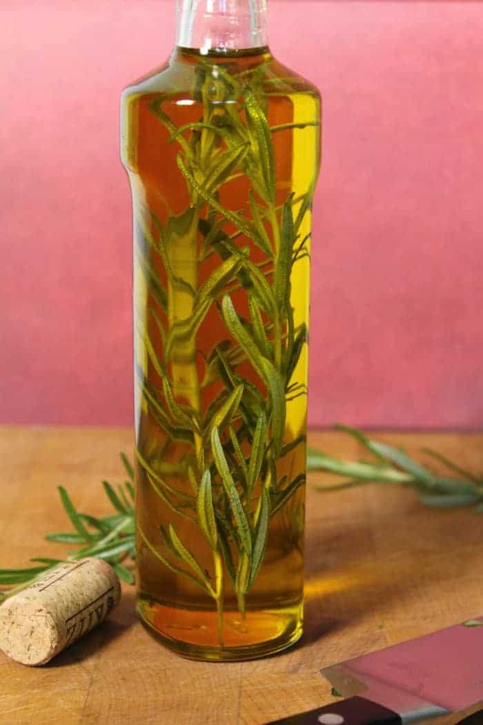 olive oil being ing fused with a few sprigs of rosemary