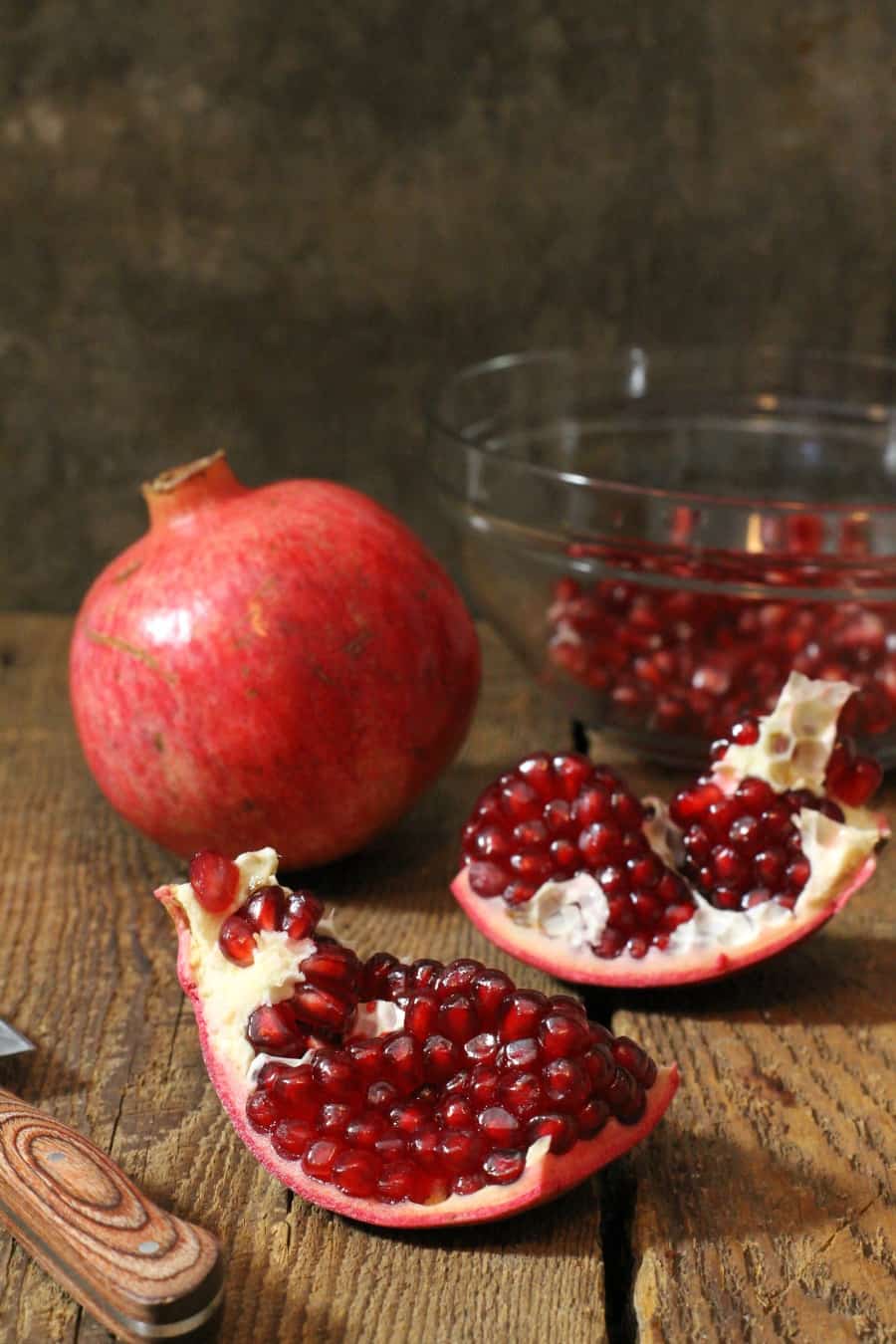 a freshly cut open pomegranate with no mess on a wooden table top, showing how to cut a pomegranate