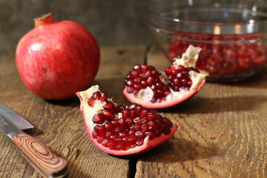 a cut pomegranate on a wooden table with zero mess