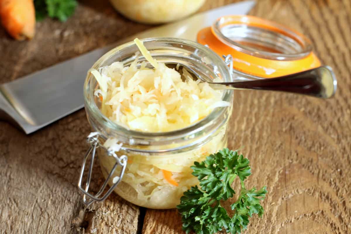 A top down close up of a jar of german sauerkraut on a wooden table.