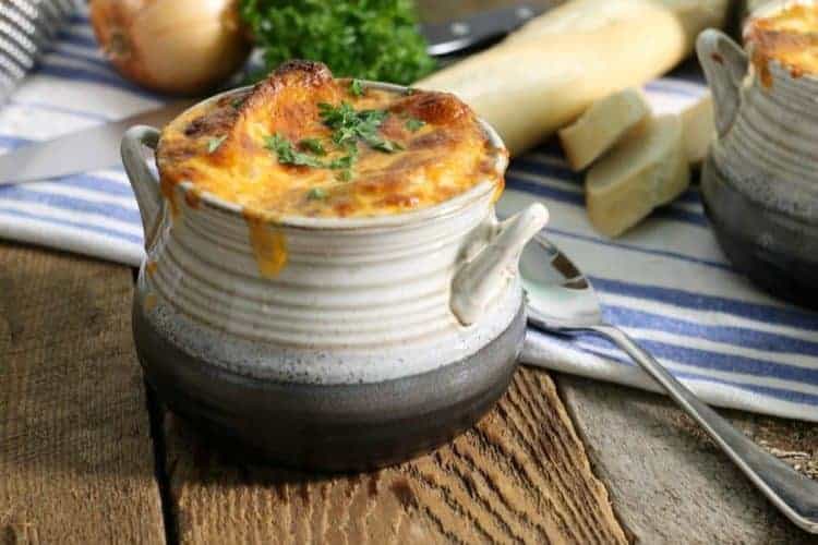 A grey stoneware bowl filled with instant pot french onion soup and topped with golden baked cheese.