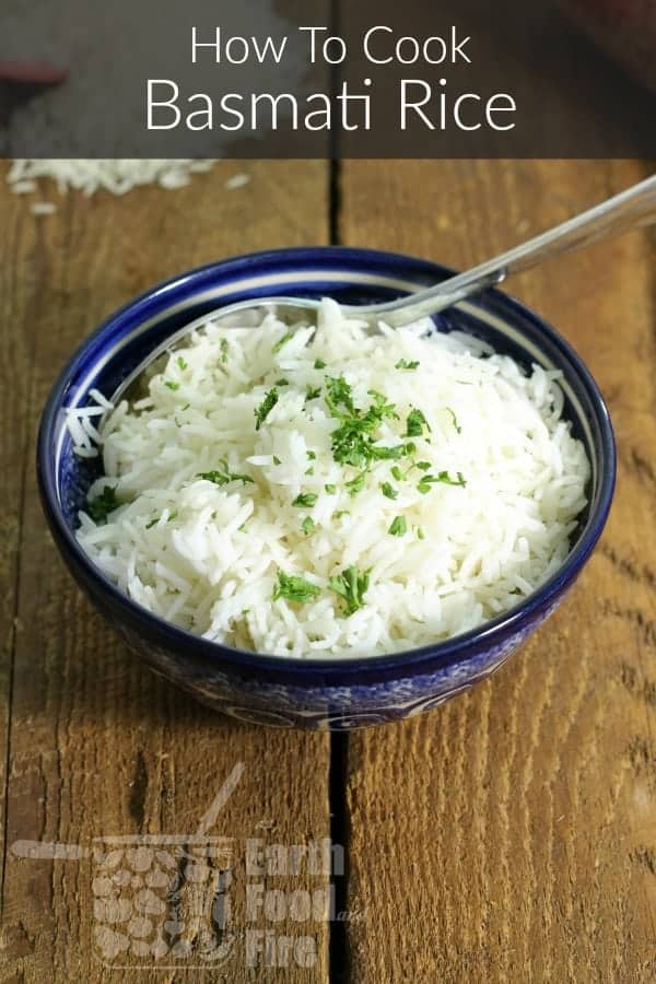 Freshly cooked basmati rice in a blue porcelain bowl garnished with chopped parsely