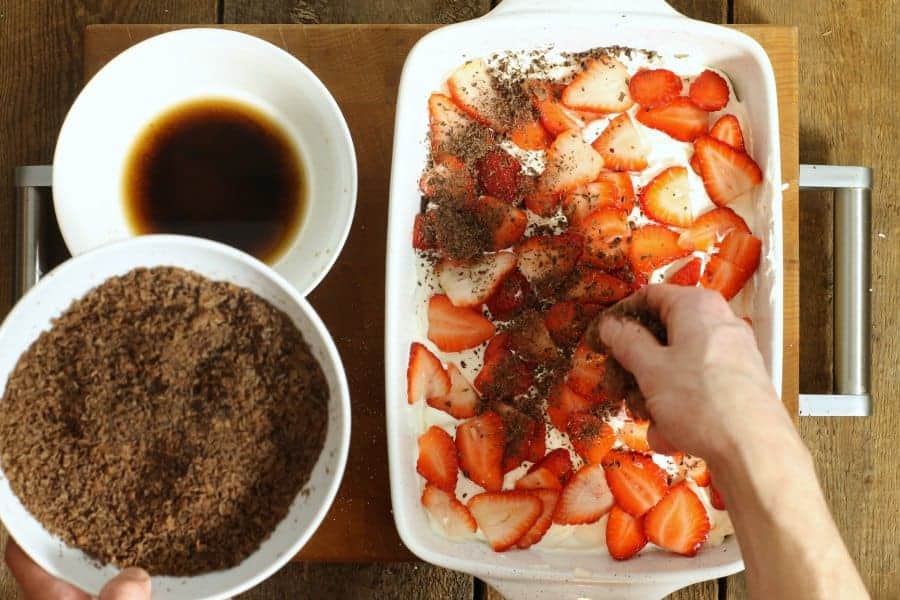 Sprinkling grated dark chocolate shavings over top of the strawberry tiramisu as garnish