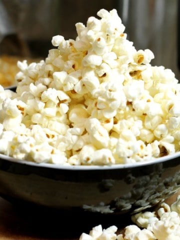 a black bowl of popped popcorn made in an instant pot.