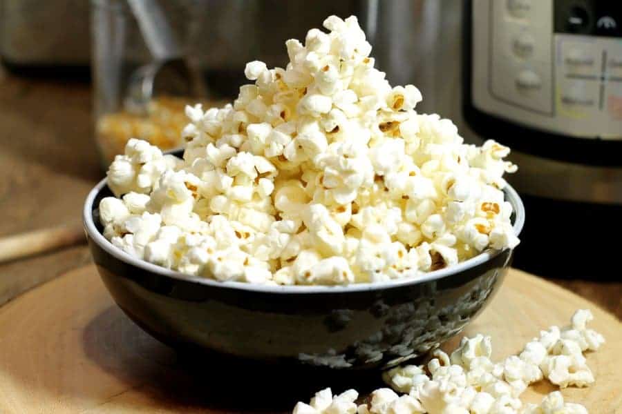 a black bowl of popped popcorn made in an instant pot.