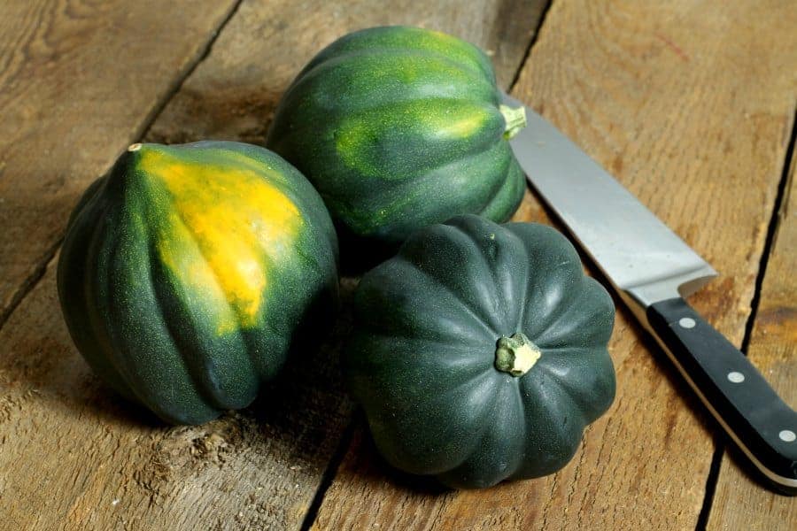 three acorn squash bunched together on a wooden table