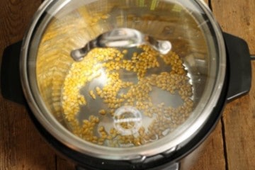 A glass lid covering an instant pot containing popcorn kernels.