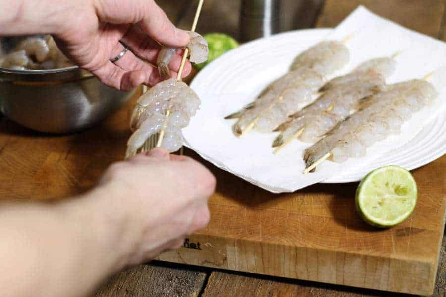 shrimp being skewered onto wooden skewers.