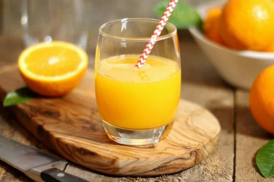 A glass of freshly squeezed orange juice on a wooden board