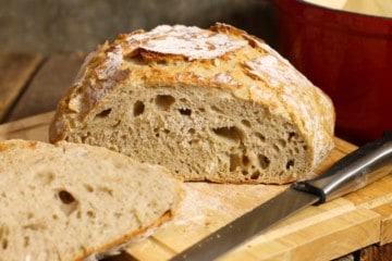 A loaf of slied no knead sourdough bread on a wooden cutting board
