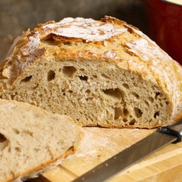 A loaf of slied no knead sourdough bread on a wooden cutting board