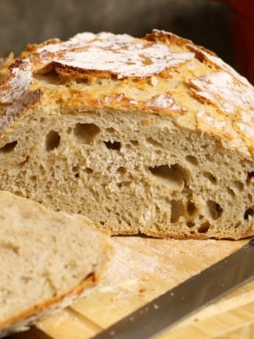 A loaf of slied no knead sourdough bread on a wooden cutting board