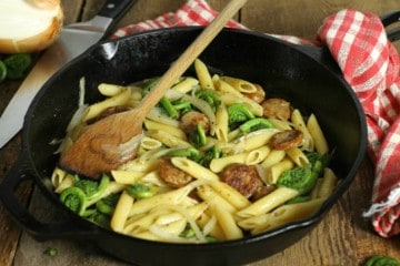 a simple fiddlehead and sausage penne pasta in a cast iron pan