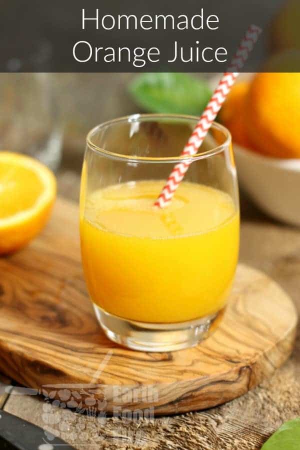 a glass of freshly squeezed homemade orange juice on a wooden serving board