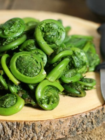 freshkly washed fiddleheads on a wooden cutting board, ready for cooking
