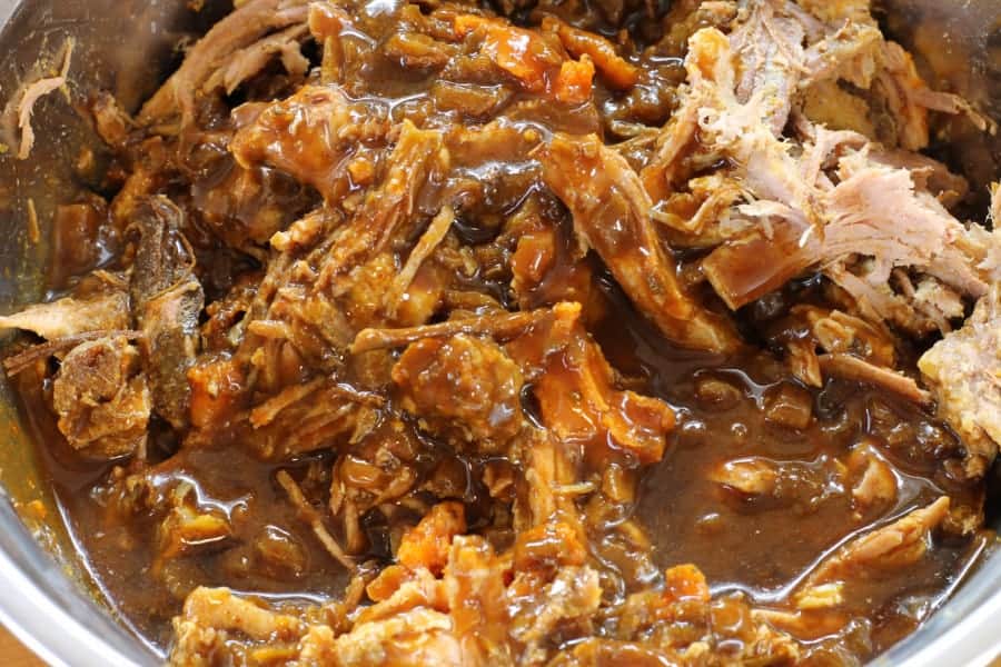 mixing the bbq sauce in with the shredded pork shoulder to make instant pot pulled pork