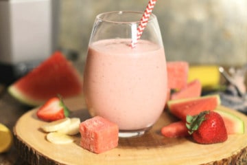 A glass of creamy strawberry banana smoothie on a wooden board