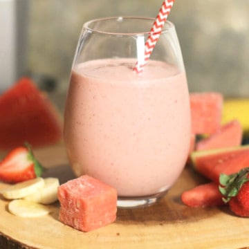 A glass of creamy strawberry banana smoothie on a wooden board