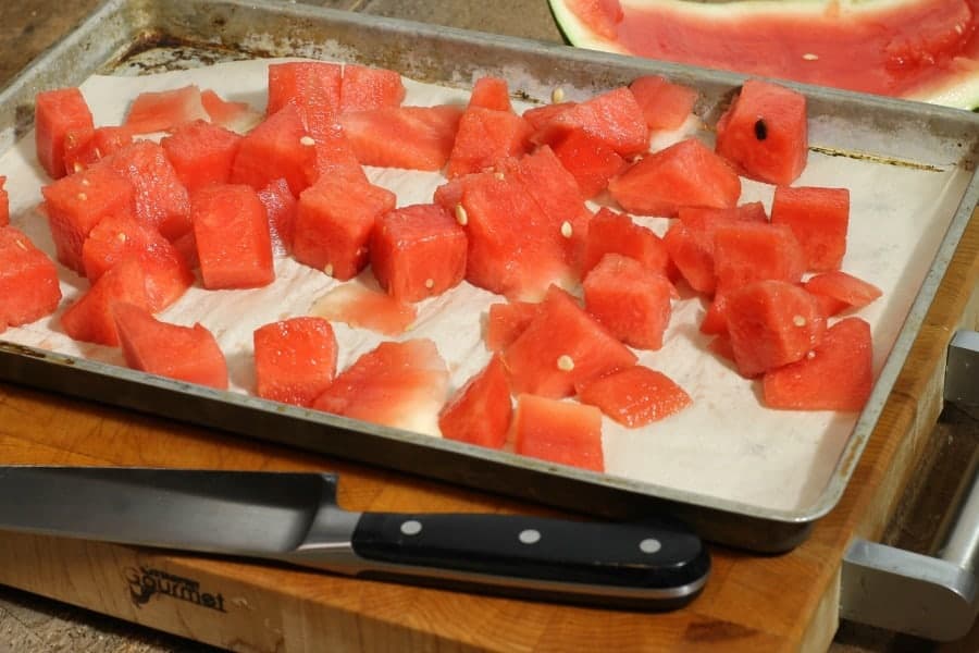 diced watermelon on a parchment lined tray ready to be frozen