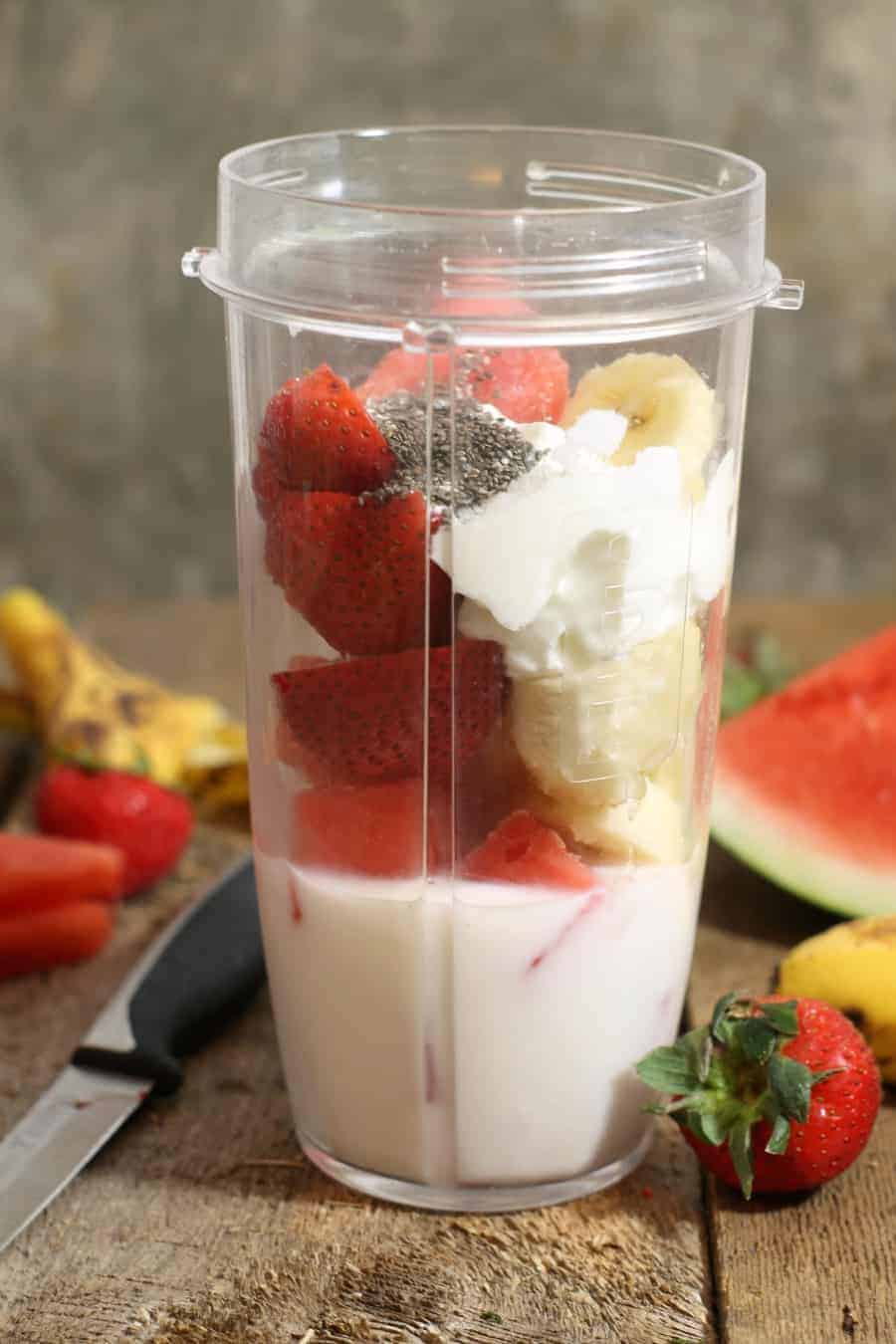 Ingredients for a Strawberry banana watermelon smoothie in a blender cup