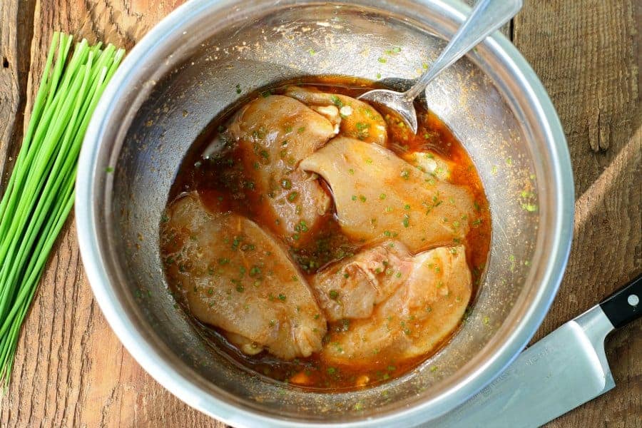 chicken breasts marinating in a metal bowl