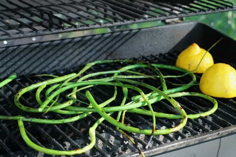 garlic scapes being grilled on a hot BBQ
